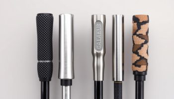 Four different hiking pole materials displayed side by side showing carbon fiber, aluminum, titanium, and composite poles
