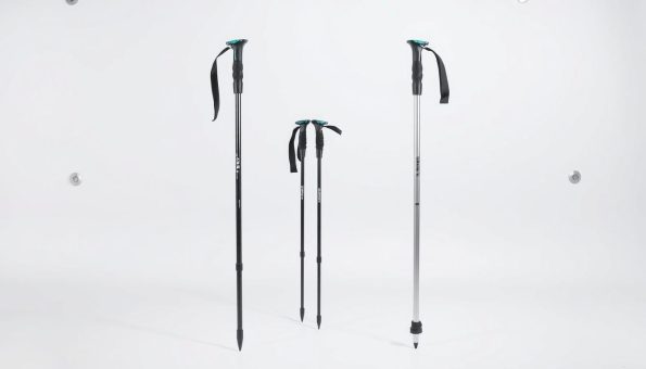 A detailed comparison of carbon fiber and aluminum trekking poles, shot in a clean, well-lit studio environment. In the foreground, two pairs of poles stand upright, one set made of sleek black carbon fiber, the other of silver aluminum. The middle ground showcases the poles from various angles, highlighting their distinct materials, weights, and grip designs. The background is a neutral white backdrop, allowing the technical details of the poles to be the sole focus. Bright, even lighting from multiple angles casts subtle shadows, emphasizing the structural differences between the two materials. The overall scene conveys a sense of informative, technical precision, suitable for illustrating a section on the material science behind high-performance trekking equipment.