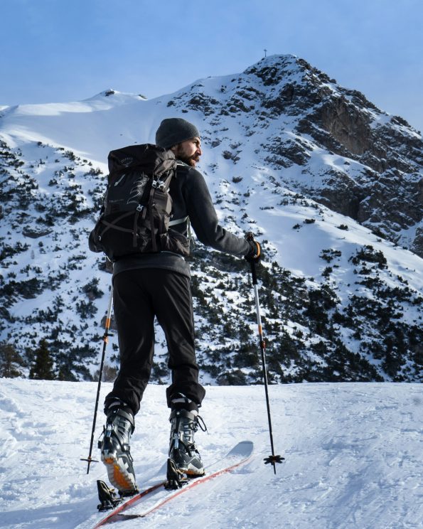 man in black jacket and blue pants standing on snow covered mountain during daytime man in black jacket and blue pants standing on snow covered mountain during daytime