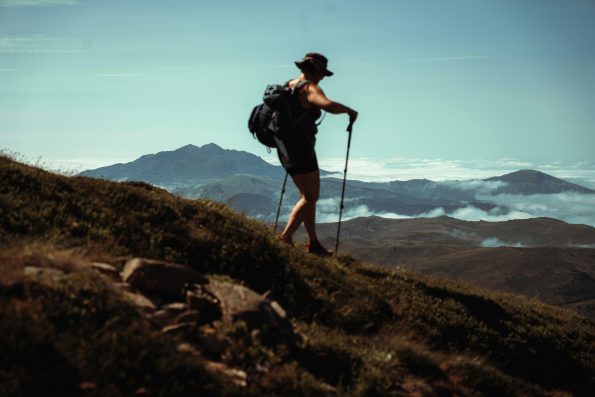 Hiker using carbon fiber hiking poles on a mountain trail compared to aluminum alloy hiking poles Hiker using carbon fiber hiking poles on a mountain trail compared to aluminum alloy hiking poles
